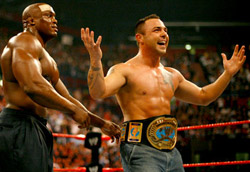 Santino Marella incredibilmente<br />vince il titolo intercontinentale” /></p>
<p><strong>Martedi 17 aprile. Ore 14.00</strong>. È il momento più atteso, quello delle interviste. La Wwe ha sempre avuto un rapporto piuttosto complesso con i giornalisti e con internet in particolare. Se il loro tentativo è quello di far apparire quanto più vero possibile ciò che accade sopra e attorno a un ring, il desiderio di chi ne parla è invece quello di palesare la realtà dei fatti, e cioè che si tratti di uno spettacolo, ancor prima che di uno sport. Solo negli ultimi anni c’è stata una minima apertura, un tentativo di sfruttare le potenzialità della comunicazione e di internet piuttosto che vederli come un problema da eliminare. E così eccomi in una stanzetta del Forum di Milano. Per arrivare nel luogo dove svolgerò le interviste, devo passare a bordoring, dove gli atleti si stanno allenando. L’uomo Wwe che mi sta accompagnando, per non dire controllando, è attentissimo a comunicarmi di non rivolgere lo sguardo sul ring mentre passo. Non sia mai che mi capiti di vedere uomini morti che in realtà si fanno una grassa risata o giganti demoniaci che per una volta si lamentano per una botta presa. Ma è proprio quello che accade.</p>
<p><strong>Martedi 17 aprile. Ore 16.00</strong>. Dopo un pò di attesa finalmente arrivano i wrestler. Non si sa chi si potrà intervistare, quando, o come. Così, quando arriva <strong>Matt Striker</strong>, poco più di un jobber, cioè uno che ne prende tante, ne dà poche e combatte nella Ecw («Un po’ come la serie C nel calcio» dice lui stesso), c’è un po’ di delusione. Ma Matt si dimostra simpatico, a dispetto dell’aria da bad guy che deve tenere sul ring. Parla anche un discreto italiano, avendo vissuto con un siciliano durante l’università. Con lui mi interrogo su quanto sia importante lo sport e quanto lo show nel wrestling («Non c’è solo entertainment, infatti potrei battere i vostri Zucchero o Eros Ramazzotti quando voglio» mi dice sorridendo), [img4]e cerco di capire quanto per un wrestler sia difficile mantenere un personaggio anche fuori dal ring. Matt ci dice allora che per facilitare tutto ciò i personaggi vengono scelti a partire dalle reali caratteristiche della vita del lottatore. «Kevin Thorn (un wrestler che interpreta un vampiro) ad esempio non ha ovviamente i denti da vampiro, ma già prima si dipingeva le unghie, aveva tatuaggi, insomma era un tipo gotico al 100%».<br />
Salutato Matt, è il momento di un suo omonimo, sicuramente più conosciuto al pubblico: <strong>Matt Hardy</strong>. Campione di coppia insieme al fratello Jeff, appare un pò stanco per la tournée, ma è disponibile anche quando tocco temi per lui delicati. Gli chiedo infatti quanto sia difficile mescolare vita reale e finzione del wrestling (qualche tempo fa il fatto reale che la sua fidanzata lo avesse lasciato per un altro lottatore era stata al centro di una <em>storyline</em> sul ring). Da vero professionista  afferma «Quando sono sul ring penso solo a combattere e a mantenere il mio personaggio, in quel momento non mi interessa quello che è successo prima», anche se poi non manca di tirare qualche frecciatina a Edge, il suo rivale in amore e sul ring. Con lui poi è interessante capire il rapporto tra lottatore e pubblico. Ad esempio, wrestler in patria amati, come John Cena, qua sono stati pesantemente fischiati. «Lo stesso succede negli Stati Uniti – ammette Matt – dove nel sud il pubblico segue pedissequamente ciò che gli viene indicato dalla federazione su chi sia il buono e chi il cattivo, mentre nel nord gli spettatori sono più furbi e fanno di testa propria. Quello che devi fare è andare sul ring, rispettare il pubblico, e fare quello che devi fare nel modo in cui sai farlo».<br />
Dopo le foto di rito con Matt, quando la giornata sembra volgere al termine, arriva invece <strong>Chris Benoit</strong>, attuale campione degli Stati Uniti ed ex detentore del titolo dei pesi massimi. Chris è appena arrivato da un allenamento, sembra un pò provato. È però il wrestler che colpisce di più: sembra commuoversi davvero quando gli si fanno i complimenti per essere “the best technical wrestler in the world”, <TABLE align=right cellpadding=3 border=0><TR><TD align=center valign=center><img src='articoli/2877_6.jpg' alt='<br />La foto scattata con Chris Benoit<br />‘><br />La foto scattata con Chris Benoit<br /></TD></TR></TABLE>oppure gli si confessa che quel maledetto incontro contro Orton, nel ferragosto del 2004, avrebbe meritato di vincerlo lui. È il volto più umano del wrestling, quello che ogni settimana attraversa mezza America in Georgia per tornare dalla moglie e dai tre figli. Si vede che, arrivato a quarant’anni, questo sport entertainment è ancora la sua passione, e che ci crede davvero.</p>
<p>E anch’io finisco per crederci davvero, quando vengo di nuovo accompagnato dall’uomo Wwe fuori dal palazzetto. È il momento di tornare a casa, chiudendo queste folli ventiquattrore in compagnia dell’incredibile mondo del wrestling. Ho cercato di comprenderlo meglio, di analizzarne le dinamiche, ma quello che penso alla fine è che «Then, for the thousands in attendance, and the millions watching at home. Let’s get ready to suck it!».</p>
				<p class=